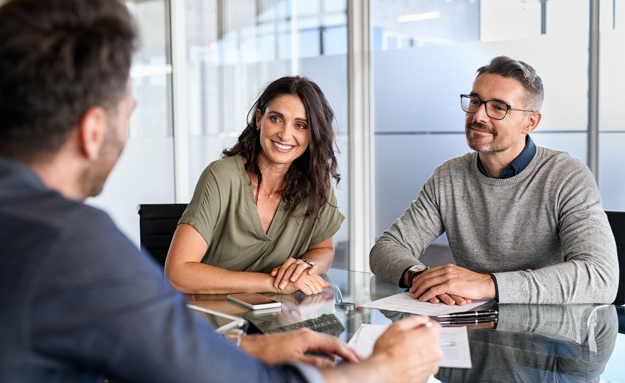 Happy couple meeting with a mortgage broker in a modern Sydney office to discuss home loan options.