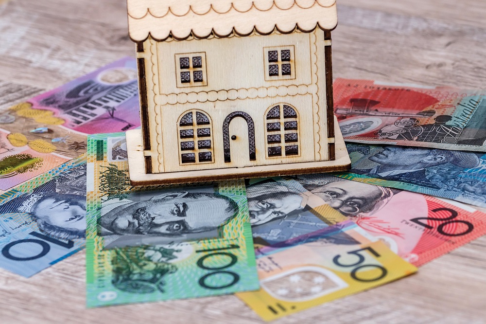 Wooden model house placed on Australian dollar banknotes