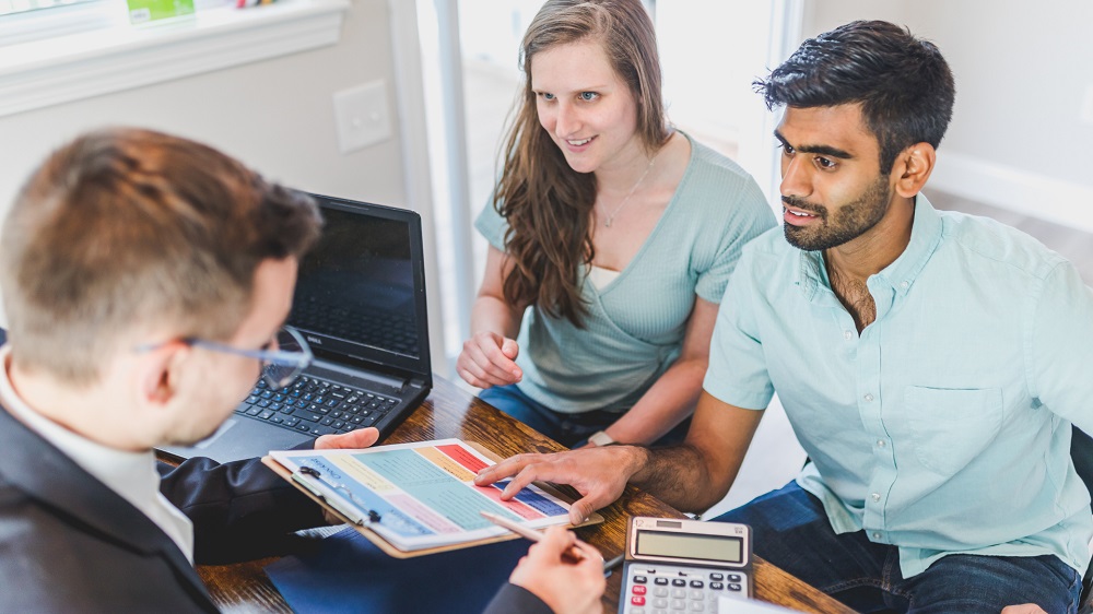 Home buyers meeting with a buyers agent to discuss property search strategy and service fees.