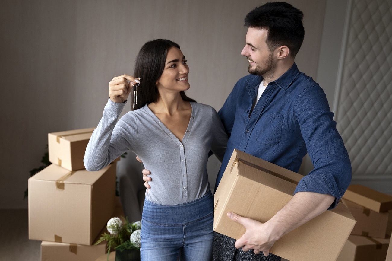 Young couple holding house keys while moving into a home in an affordable family-friendly suburb in Australia.
