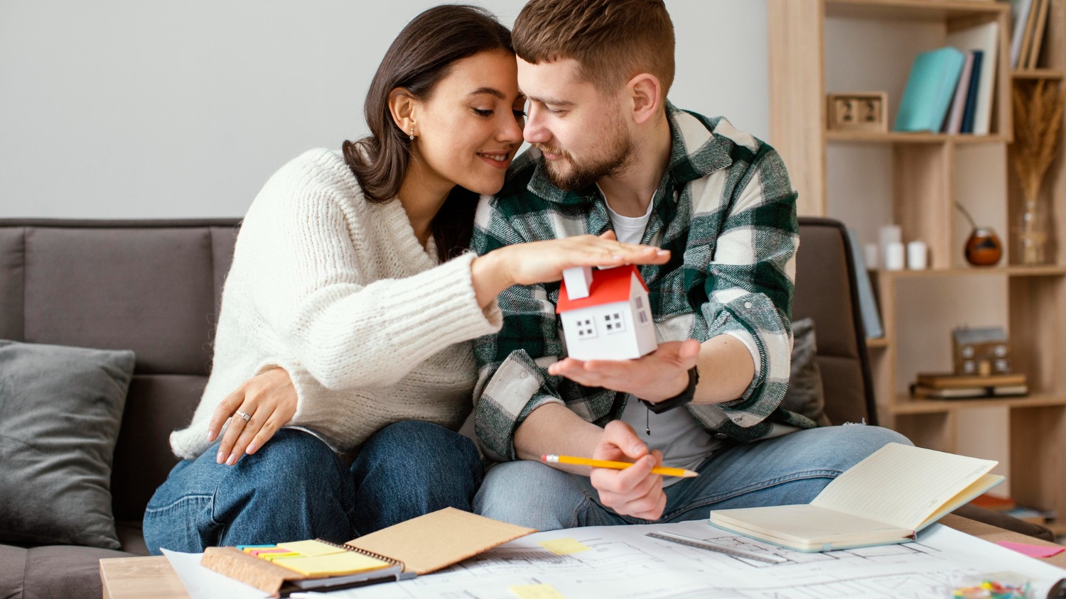 First home buyer couple holding a house symbol representing the First Home Guarantee Scheme and buying a home with a 5% deposit in Australia.