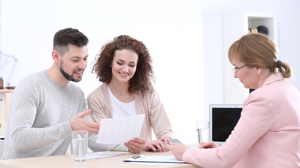 Home buyers reviewing mortgage options with a broker while comparing fixed and variable loan rates.