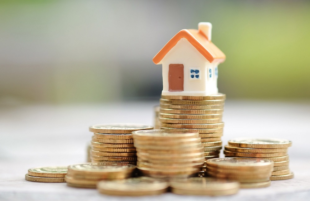 small model house sits on top of stacked coins